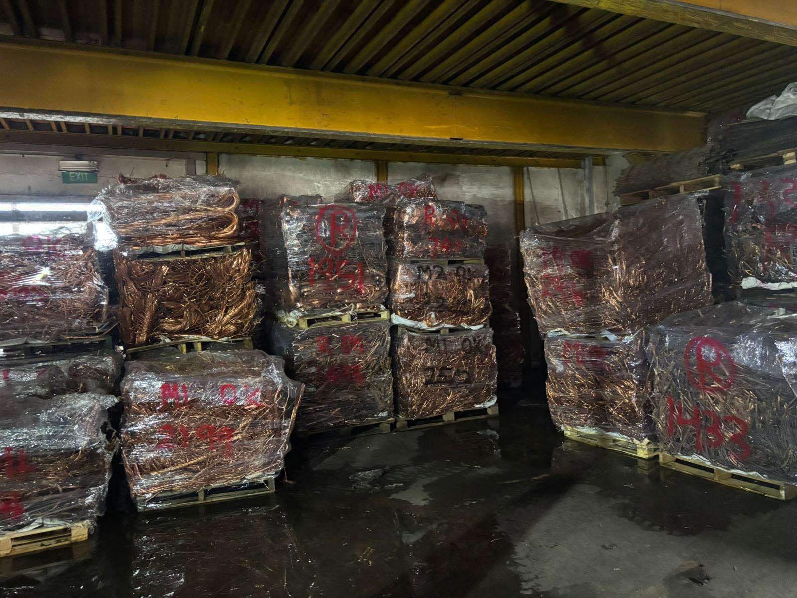 Graded and wrapped copper bales marked with grade and weight, palletised in the Ogoo Recycle store ready for export